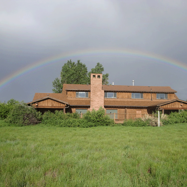A rainbow over a house on a hill