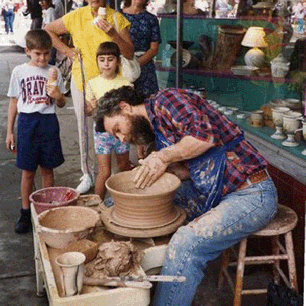 Potter throws large bowl while children look on