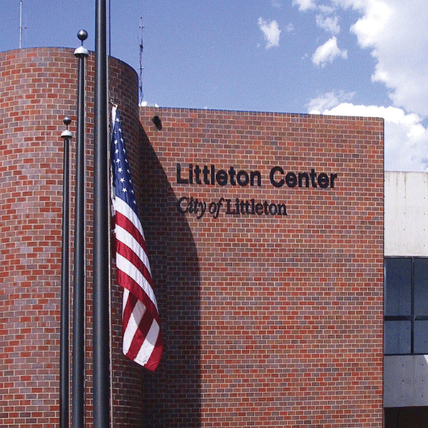 American flag in front of Littleton Center brick building with blue sky