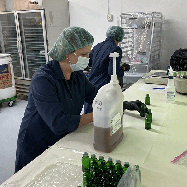 Person filling glass bottles in a factory setting